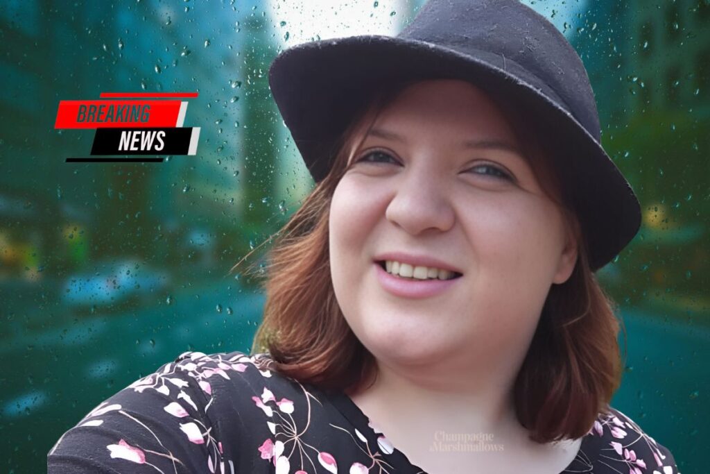 Misty Severi, wearing a black hat and a floral-patterned top, smiles in front of a rain-covered window with a blurred cityscape in the background. The words 'Breaking News' are displayed in bold red, white, and black font in the top left corner.